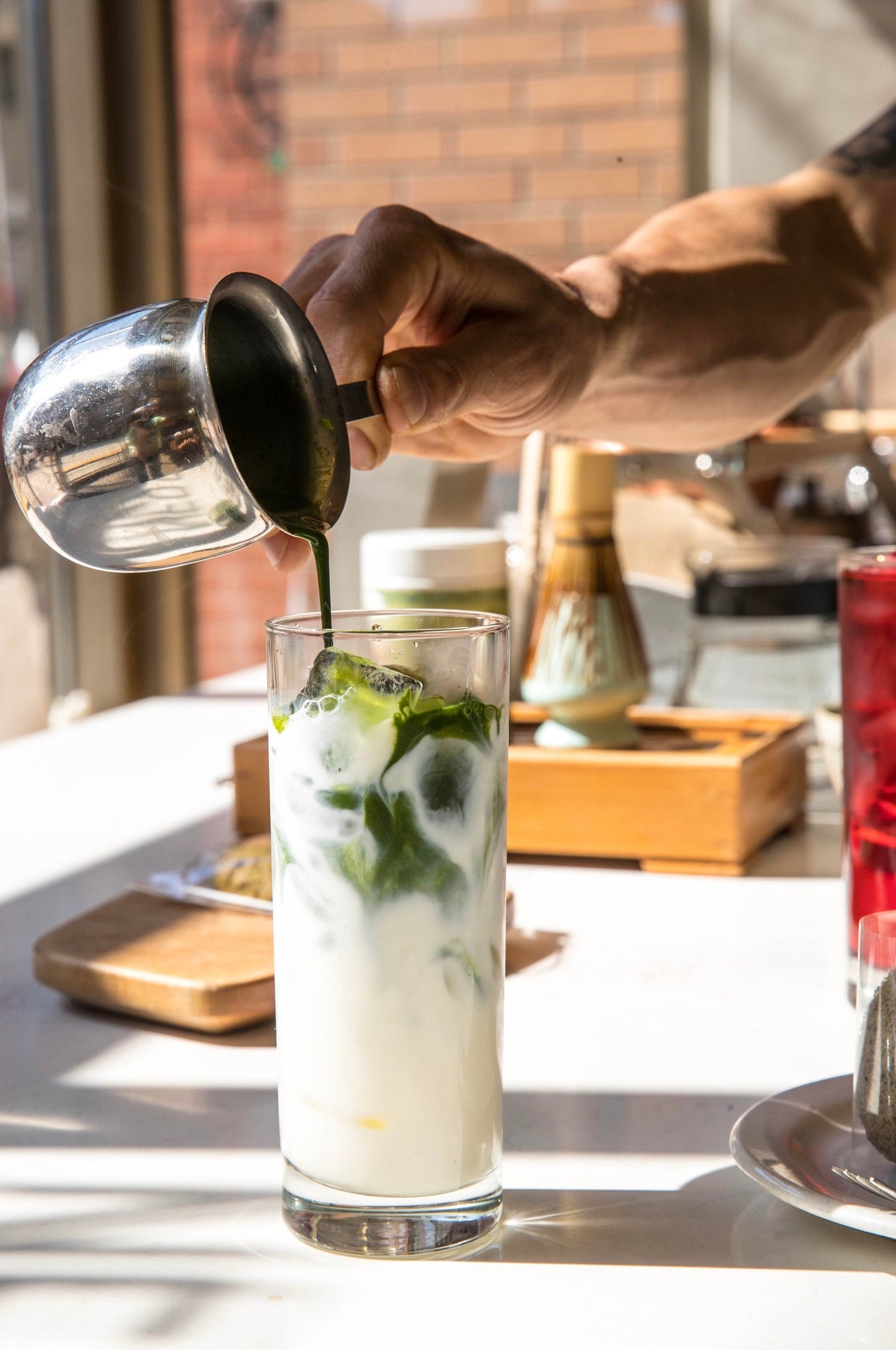 Matcha being poured over an iced matcha latte